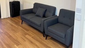 A living room with a grey sofa, a black suitcase, and a radiator.