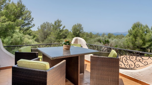 A balcony with wicker furniture, a table, and a view of trees and mountains. - Holiday Home 'Casa Luisa' with Sea View, Private Pool and Wi-Fi (Betlem)