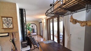 A kitchen with a wooden table, hanging utensils, and a trash bin. - Holiday Home 'Casa Luisa' with Sea View, Private Pool and Wi-Fi (Betlem)