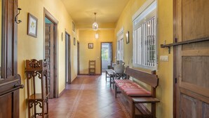 Un pasillo con puertas de madera, un banco, una mesa y una lámpara colgante.