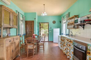 A kitchen with a dining table, chairs, a refrigerator, and a microwave.