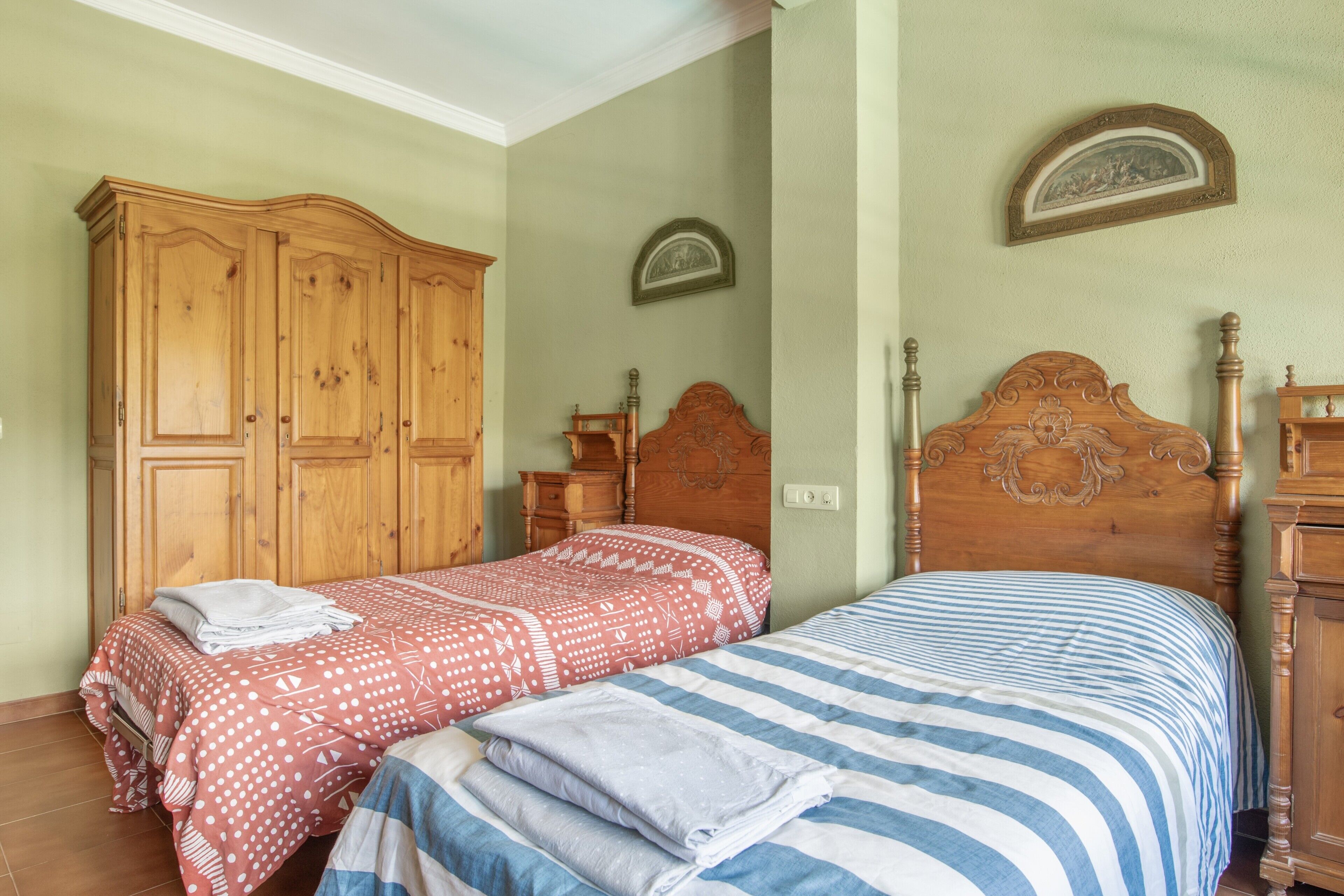 Een slaapkamer met twee bedden, houten meubels en een aan de muur hangend schilderij.