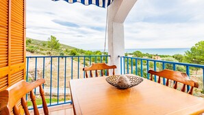 Une table en bois, un saladier, deux chaises et une vue sur la mer.