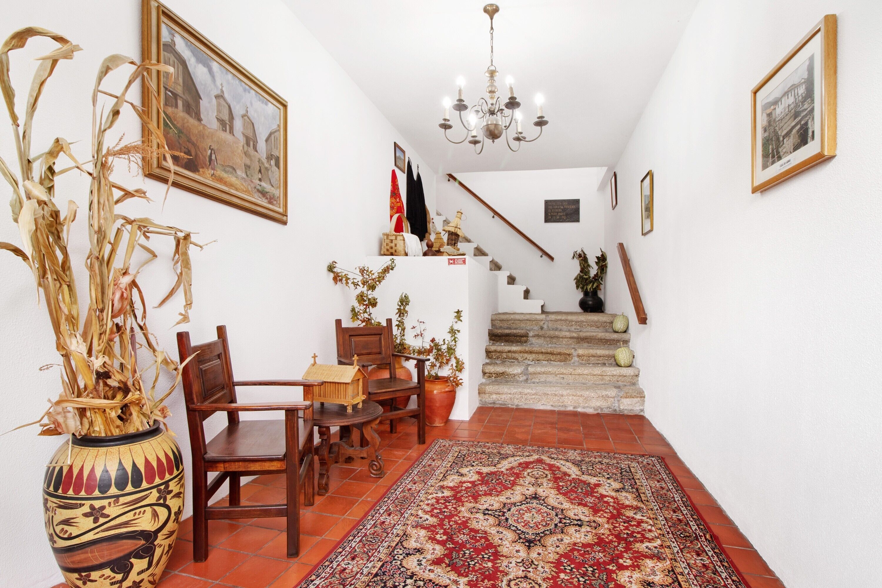 A staircase leading to a second floor, a dining area with a table and chairs, a decorative vase, and a chandelier.