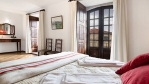 Un dormitorio con cama, escritorio, silla y ventana con cortinas.