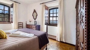 Une chambre à coucher avec un lit, une commode, un miroir et des fenêtres.