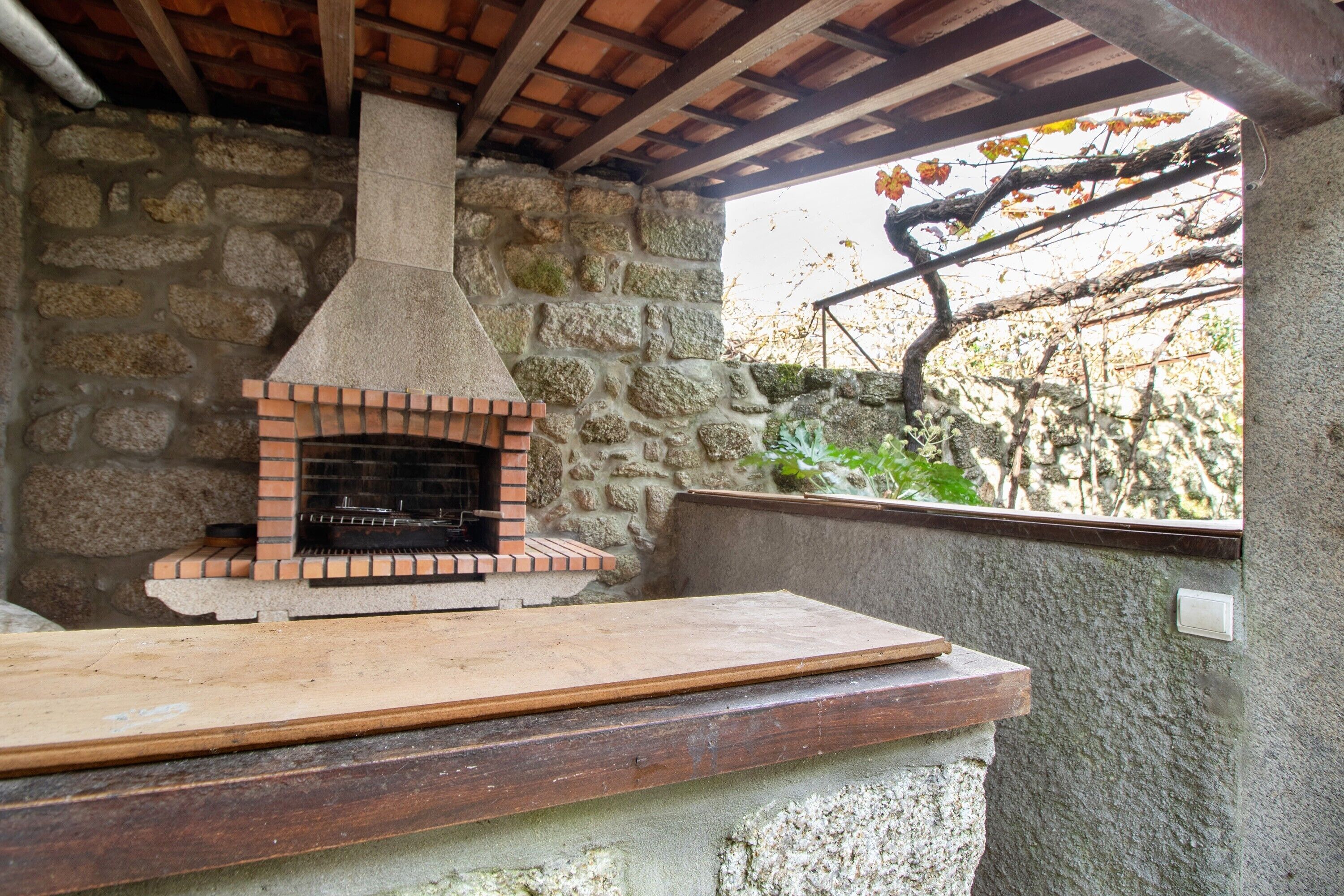 Un forno in pietra con base in mattoni, un piano di lavoro in legno e una parete in pietra.