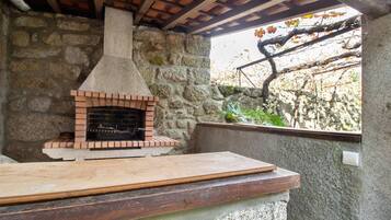 A stone oven with a brick base, a wooden countertop, and a stone wall.