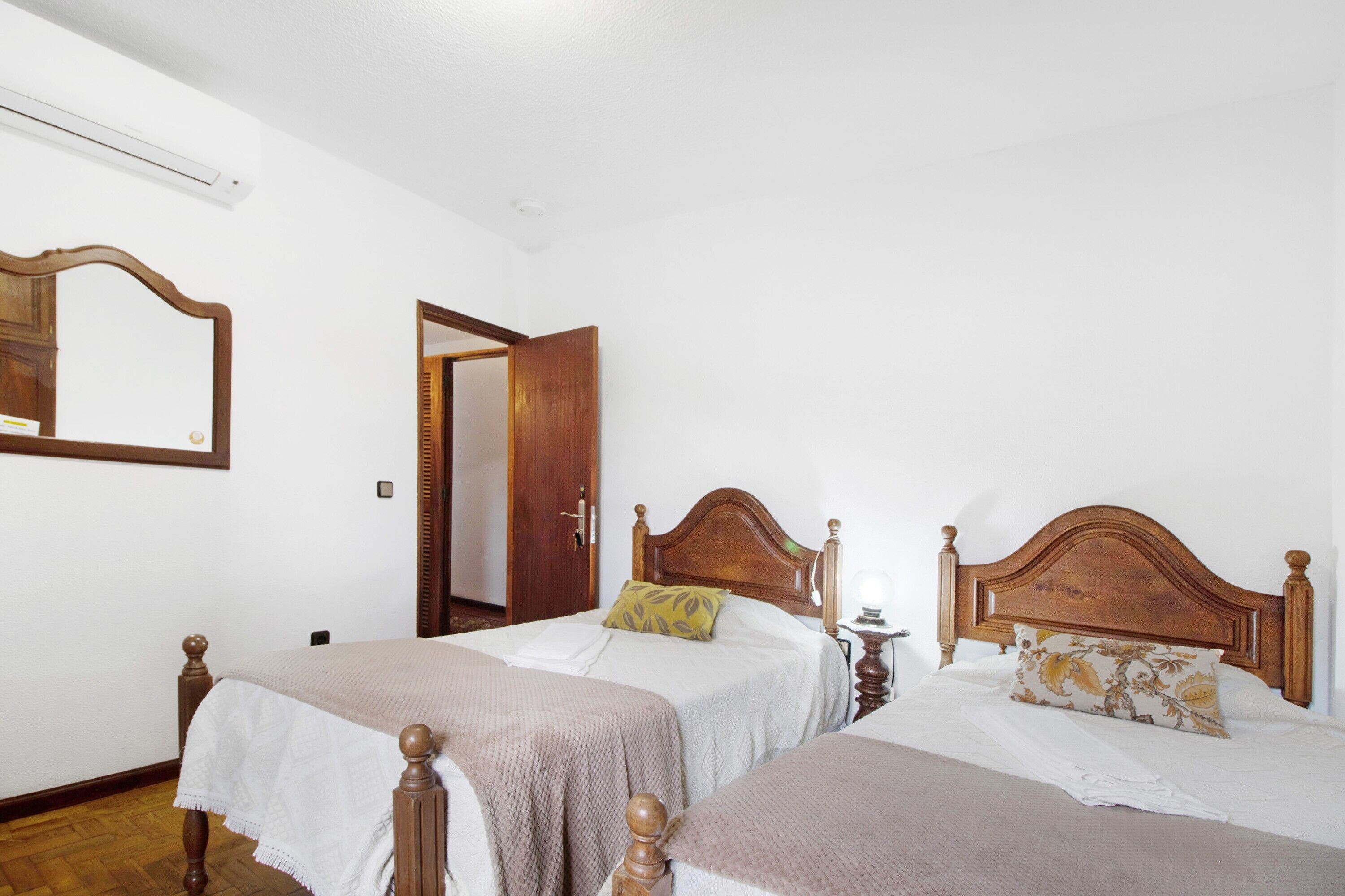 Una habitación con dos camas de madera, un espejo y una puerta.