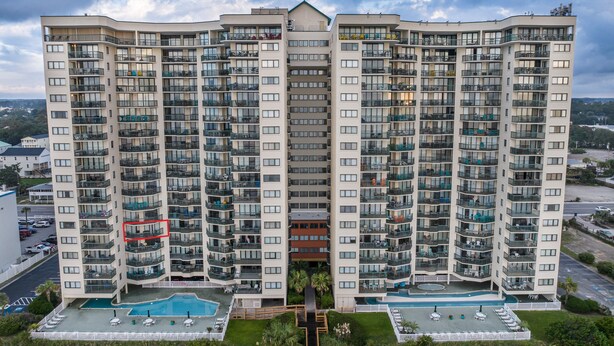 Un edificio de gran altura con múltiples balcones, un patio central y una piscina.