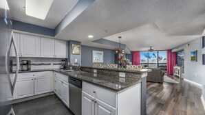 Una cocina moderna con armarios blancos, encimeras de granito y lavavajillas.