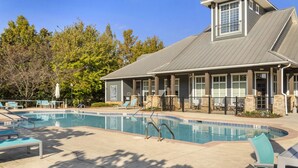 Une piscine avec des chaises longues et un espace patio couvert.