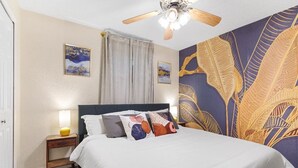 Ein Schlafzimmer mit einem Bett, einem Nachttisch, einem Deckenventilator und einem großen Wandteppich.