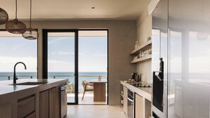 A modern kitchen with a large island, built-in appliances, and a view of the ocean. - Unique luxury Ocean view villa steps from the beach (Cóbano)