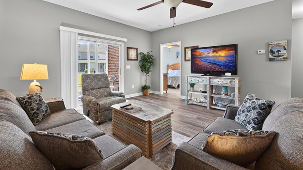 A living room with a ceiling fan, a television, and a coffee table.
