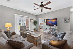 A living room with a ceiling fan, a television, and a coffee table. - Heatherstone 1387 | Relaxing Myrtle Beach Vacation (Myrtle Beach)