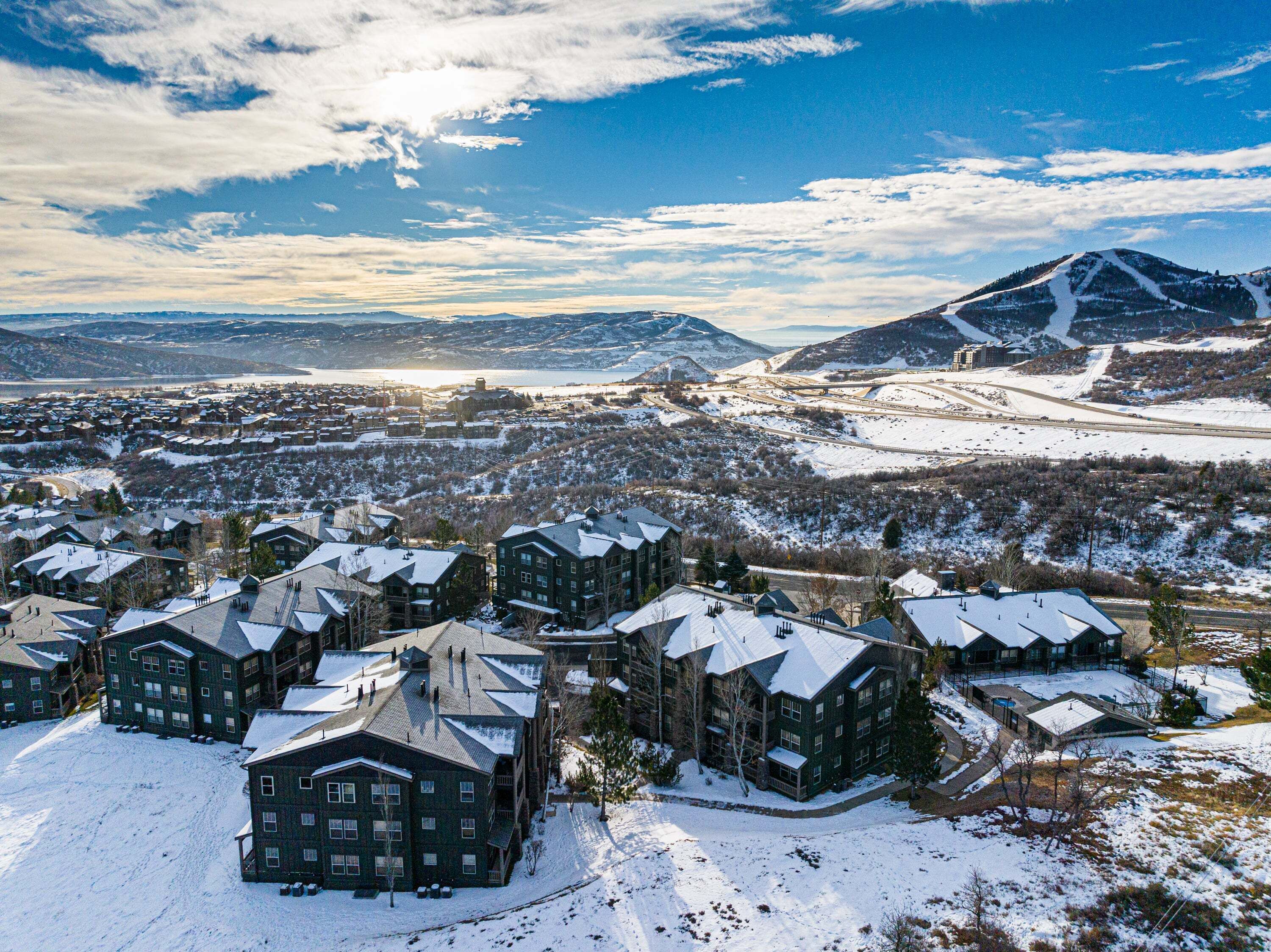A snow-covered residential area with multiple houses, a mountain in the background, and a clear sky.