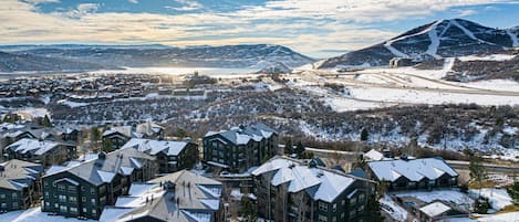 Ett snötäckt bostadsområde med flera hus, ett berg i bakgrunden och en klar himmel.