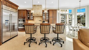 Una cocina moderna con electrodomésticos de acero inoxidable, armarios de madera y una isla central con taburetes de bar.