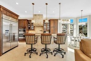 A modern kitchen with stainless steel appliances, wooden cabinets, and a central island with bar stools.