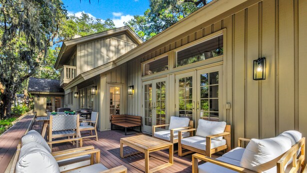 Una terraza de madera con mobiliario exterior, incluyendo sillas y un banco.