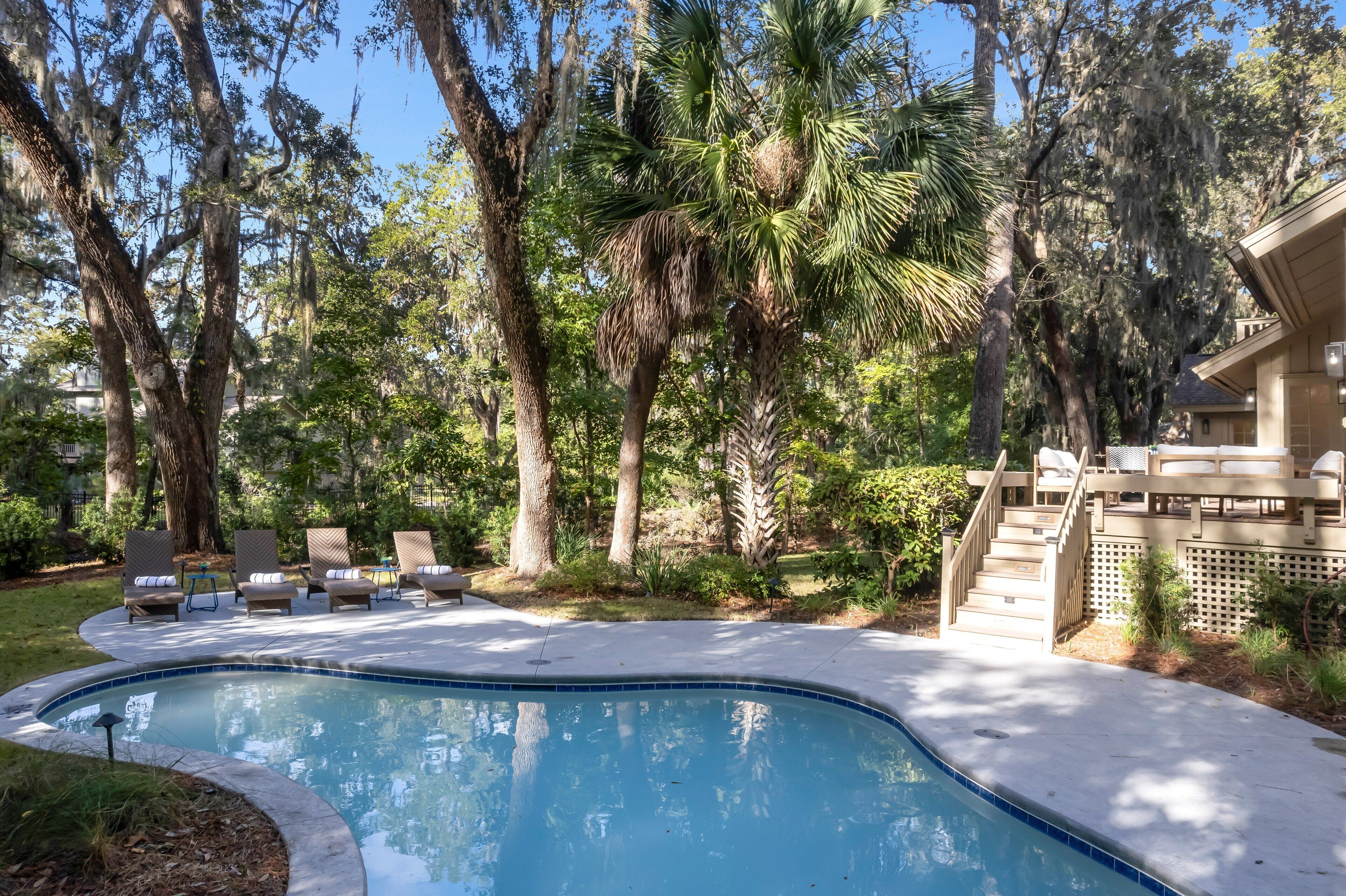 A swimming pool with lounge chairs and a staircase leading to a deck.