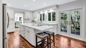 Una cocina amplia con gabinetes blancos, una isla grande y suelo de madera.