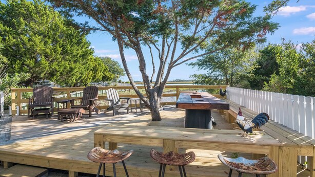 An outdoor deck with wooden furniture, a tree, and a rooster.