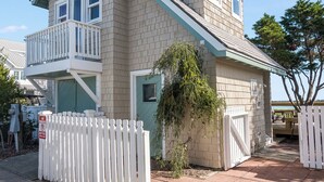 A two-story house with a balcony, a wooden deck, and a white picket fence.