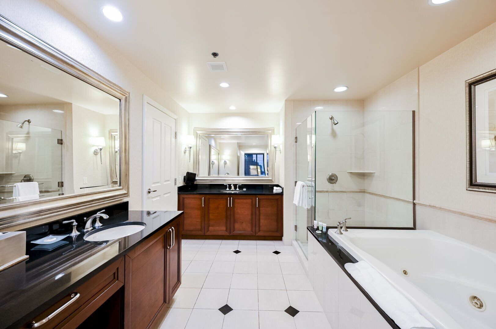 Une salle de bain moderne avec deux lavabos, un grand miroir, une baignoire et un espace douche.