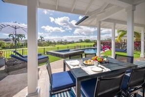 An outdoor patio with a pool, lounge chairs, and a table set for breakfast.