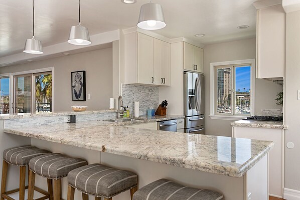 A modern kitchen with a large island, stainless steel appliances, and a view of the marina.