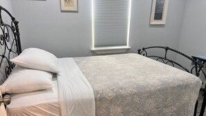 A bed with a patterned bedspread, a metal headboard, and white pillows. - Charming 3-bedroom cottage in serene Aransas Pass with AC, WiFi (Aransas Pass)