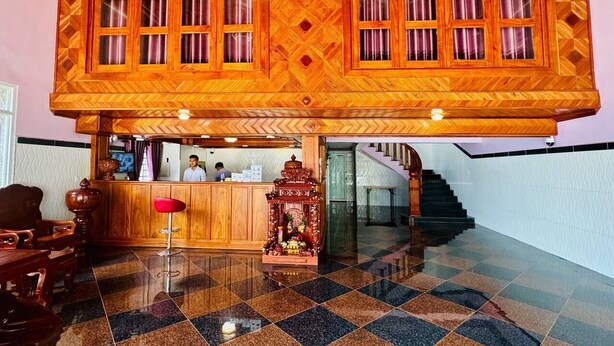 A reception area with a check-in counter, a staircase, and a decorative altar. - The Cozy Corner-Budget Hotel (Kampot)