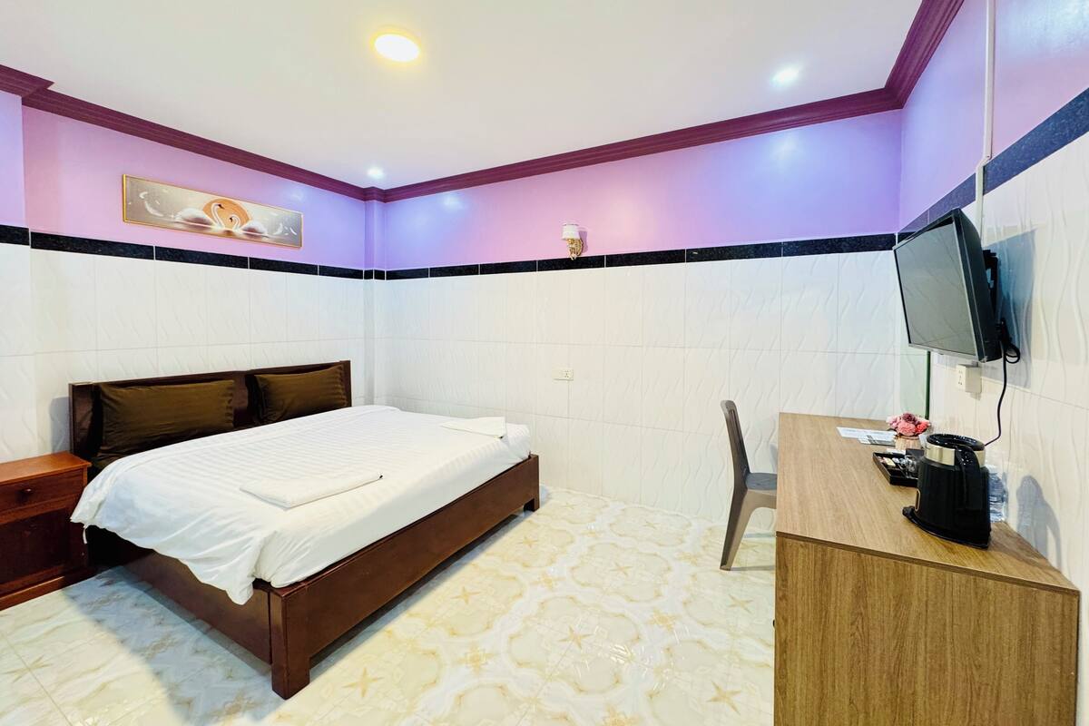 Ein Schlafzimmer mit Bett, Nachttisch, Schreibtisch, Stuhl und einem an der Wand montierten Fernseher.