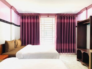 Une chambre d’hôtel avec un lit, un canapé, une télévision et une fenêtre avec des rideaux.