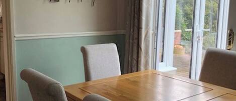 Un comedor con una mesa de madera y cuatro sillas grises. Se observa una obra de arte abstracta colgada en la pared sobre la mesa.