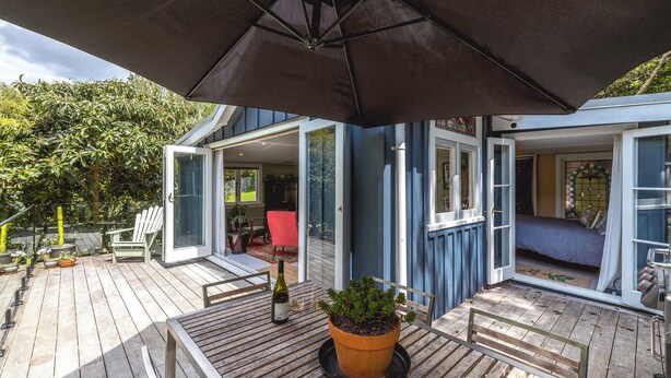 A wooden deck with a table, chairs, and a potted plant. - Hillside Hideaway - Our Island (Waiheke Island)