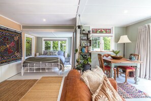 Une pièce spacieuse comprenant un lit, un coin repas et une grande fenêtre laissant entrer la lumière naturelle.