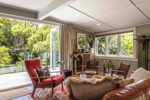 Un salon chaleureux avec un fauteuil rouge, un canapé en cuir marron et un meuble en bois orné de plantes.