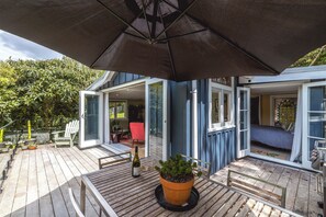 Une terrasse en bois avec une table, des chaises et un pot de fleurs.
