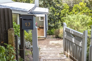A wooden staircase leading to a house with a mailbox marked '13'. - Hillside Hideaway – Romantic Cottage Escape (Waiheke Island)