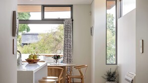 Une cuisine moderne avec un coin repas, dotée d’une grande fenêtre, d’une plante en pot et d’un climatiseur intégré.