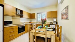 Eine moderne Küche mit Holzausbau, einem eingebauten Ofen, einer Mikrowelle und einem Essbereich mit Holztisch und Stühlen.