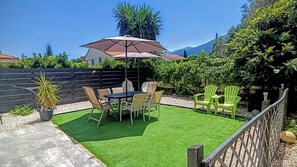 Um pátio com mesa e cadeiras, um vaso de planta e vista para as montanhas.