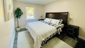 A bedroom with a bed, a nightstand, a potted plant, and a window. - Entire house 3BR, Pets, kitchen, Parking, Laundry, Large Fenced backyard, WiFi (Kitchener)