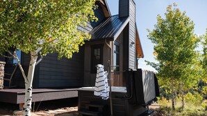 A cabin with a chimney, a covered porch, and a small deck area.