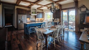 Una cocina amplia con pisos de madera oscura, una isla central y un comedor con sillas blancas.