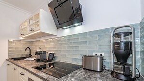 A modern kitchen with a built-in stove, a coffee maker, and a toaster. - This one love - Cozy vacation apartment for up to 3 people in Alt (Sylt)