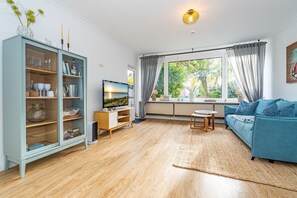 Una sala de estar con televisión, sofá y mueble.